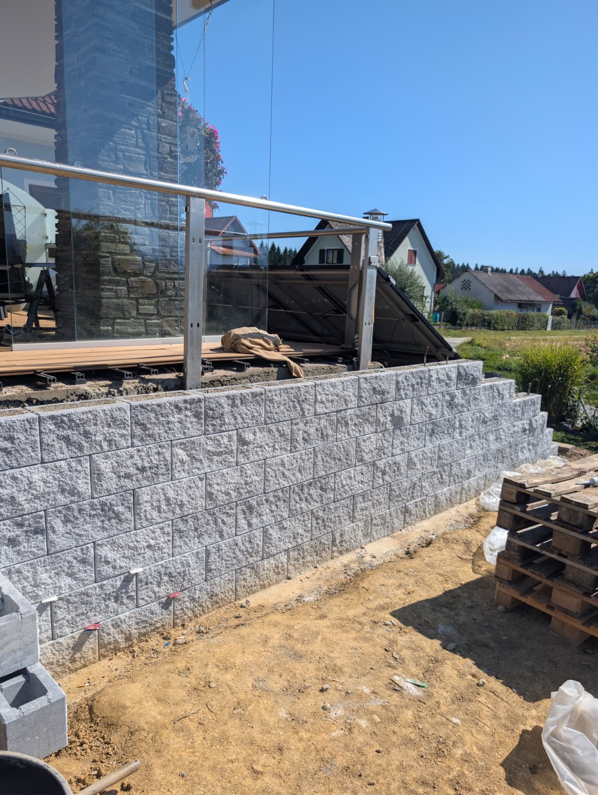 Stützmauer aus Steinblöcken unter Terrasse mit Glasgeländer